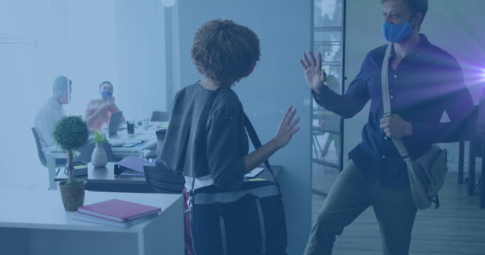 Image of green light spot over diverse man and woman greeting by touching their feet at office - Powered by Adobe