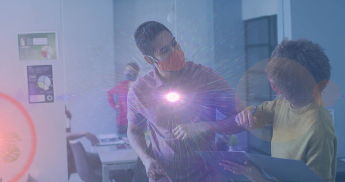 Image of pink light spot over diverse man and woman greeting by touching elbows at office - Powered by Adobe