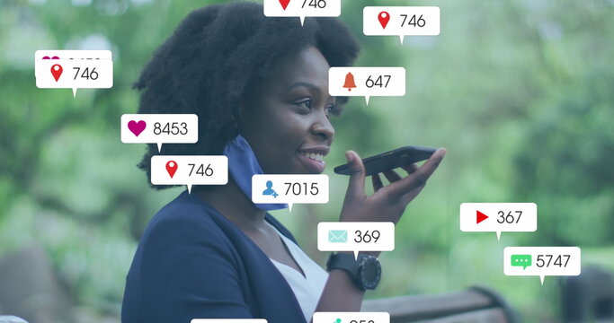 Image of social media icons with growing numbers over african american woman using smartphone