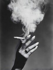 Fototapeta premium An elegant hand with manicured nails holding a lit cigarette releasing smoke in a monochrome portrait view.