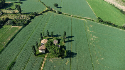Casolare di campagna immerso in un prato verde visto dal drone
