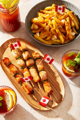 Chicken skewers closeup and other Canada Day party food with poutine, hot dogs, decorated with Canadian flag