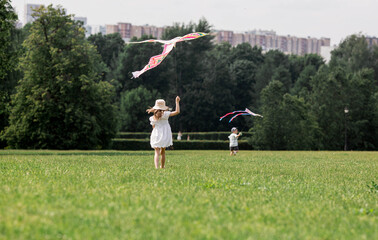Children in the summer park. Children walk and fly a kite in the fresh air. Warm family moments or...