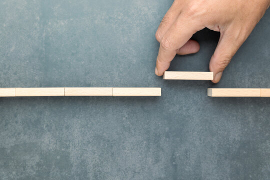 Conceptual image of a hand placing a wooden block to bridge a gap, symbolizing connection, problem-solving, or overcoming obstacles. Useful for business, teamwork, and personal growth themes
