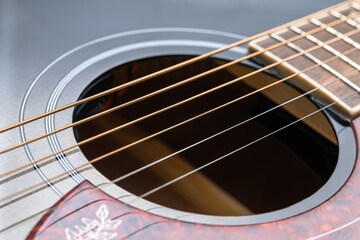 Detailed view of the soundhole and rosette of an acoustic guitar, showing bronze strings and a...