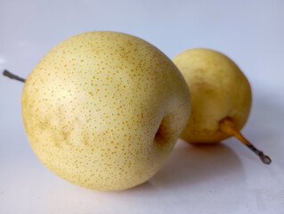 Two ripe, yellow Asian pears with visible brown specks, showcasing their characteristic round shape and smooth skin on a plain background.