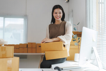 Young asian woman entrepreneur is holding cardboard boxes for delivery to her customers