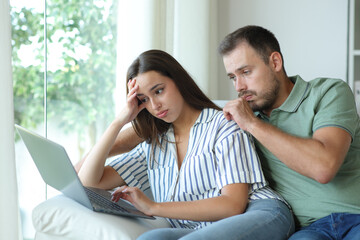 Stressed couple complaining checking laptop after mistake