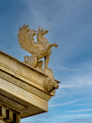 A griffin sculpture atop the National Academy embodying mythological grandeur and classical artistry. Cultural travel to Athens, Greece.