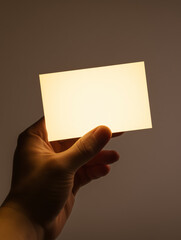Hand holding a glowing rectangular card, simple background