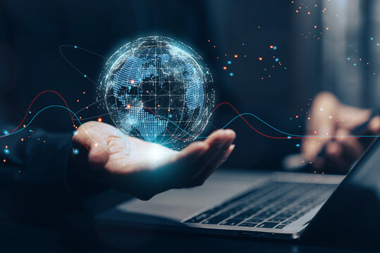 Global network and digital connection: A businessman's hand holds a glowing holographic globe above a laptop, surrounded by abstract digital waves and data points representing worldwide communication.