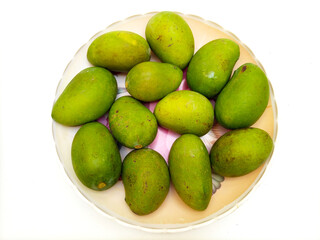 Fresh green mango fruit in a plate isolated on white background, top view, tropical fruit, unripe mangoes for pickle