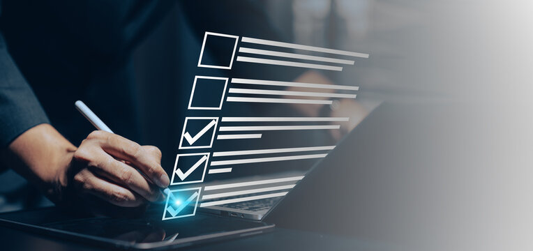 Digital document checklist and online form completion: Close-up of a hand using a stylus on a tablet to interact with holographic checklist boxes and digital document icons above a laptop.