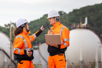 Engineers Collaborating at Industrial Site with Storage Tanks, Team of Engineers Conducting...