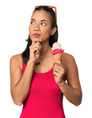 Young Filipina in bikini with ice cream looking sideways with doubtful and skeptical expression.