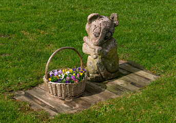 Composition of a stone figurine and a basket of flowers.