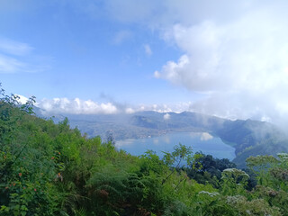 View of the hillside in Kintamani Bangli, Bali covered by greenery and mist in the morning.