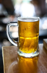 Image of a cold beer mug. The mug is of clear glass, highlighting the golden and bright color of the beer.