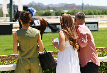 Personas de público observando a un caballo de carreras en el hipódromo