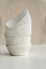 Close up shot of  paper forms for baking mafins against a biege backgroun