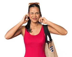 Naklejka premium Young Filipina with beach bag covering ears with fingers, stressed and desperate by a loudly ambient.