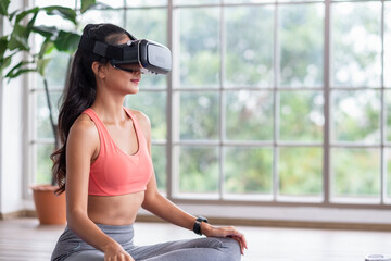 Asian woman wear virtual reality glasses choosing training yoga class online at home