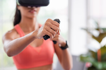 Asian woman wear virtual reality glasses and train boxing with joystick control at home