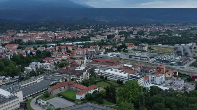 Modern glass-and-steel ICO IV and other buildings in Ivrea's Unesco-listed Olivetti district, framed by the Alps and Mount Mombarone in the background, drone pull out hot, slow motion, cloudy sky