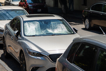 Fototapeta na wymiar Protective reflective surface under the windshield of passenger car parked on the city street on hot day, heated by sun rays inside car. Sunshade, Heat protection, auto accessory concept