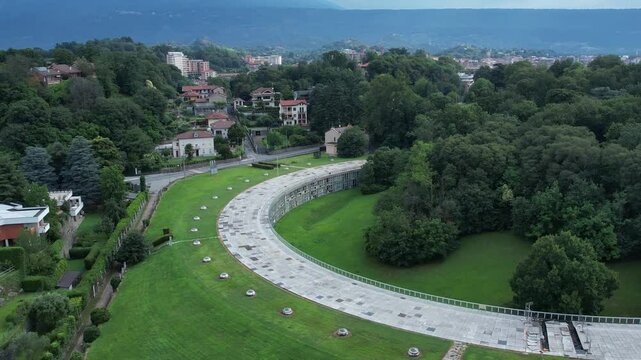 Talponia, the semi-subterranean residential unit in Ivrea, Piedmont, designed by Gabetti Isola in 1968, set in a curved green park at the city forest edge, drone pull away shot slow motion, Italy