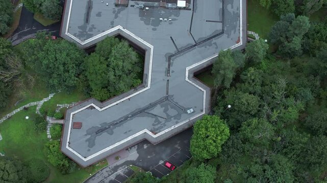 Top-down drone shot of Olivetti&rsquo;s historic company canteen in Ivrea, designed to harmonize with nature, surrounded by dense forest, example of humane modernist industrial architecture, , slow motion