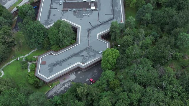 Top-down drone shot of Olivetti&rsquo;s historic company canteen in Ivrea, designed to harmonize with nature, surrounded by dense forest, example of humane modernist industrial architecture, , slow motion