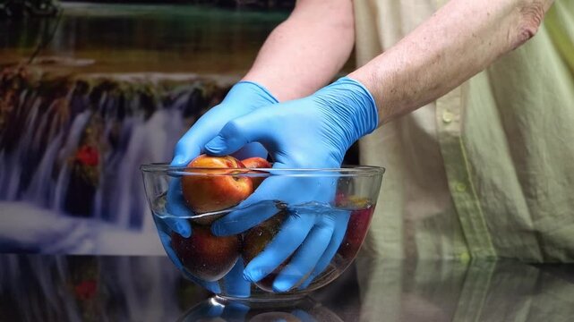 Le mani dell'uomo prendono le pesche dalla ciotola con l'acqua, movimento rallentato