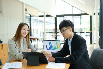 Two business people discuss financial strategy and collaborate with colleagues.