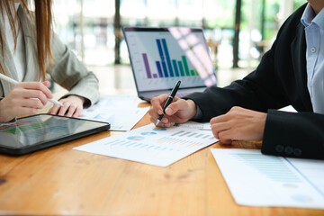 Two business people discuss financial strategy and collaborate with colleagues.