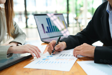 Two business people discuss financial strategy and collaborate with colleagues.