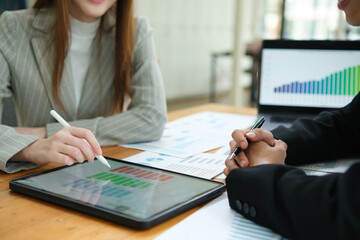 Two business people discuss financial strategy and collaborate with colleagues.
