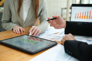 Two business people discuss financial strategy and collaborate with colleagues.