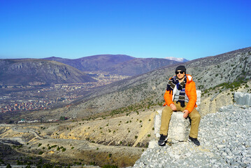 Ecotourism in Bosnia and Herzegovina: a man takes a rest during a hike at a viewpoint. A tourist...