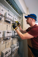 Electrician working on a modern electricity power meter station in a building.