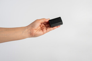Black DSLR camera battery and hand on white background