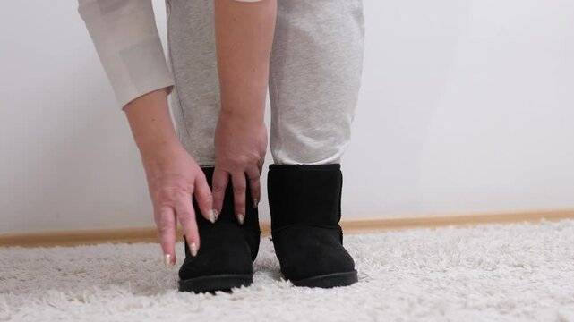 woman puts on new winter shoes touches with hands