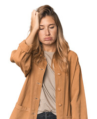 Caucasian blonde woman in studio tired and very sleepy keeping hand on head.