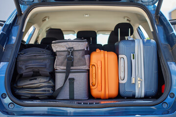 Full car trunk packed with suitcases, backpacks and bags. Vehicle filled with luggage ready for travel. Moving or road trip concept