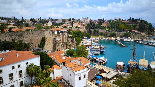 Aerial view of a marina with boats docked in turquoise water and red-roofed buildings nearby - Powered by Adobe