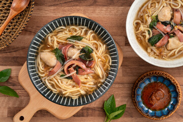 Taiwanese squid thick noodle soup in ceramic bowl on wooden table background.