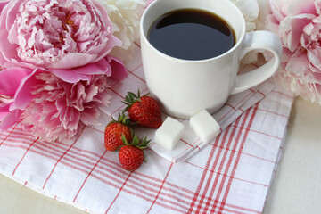 A cup of coffee and peonies flowers on the table. Cozy morning coffee with peonies for relaxation.