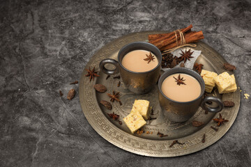 Mugs of Indian masala chai and sweets on a metal try