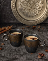 Mugs of Indian masala chai and sweets on a metal try
