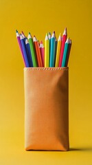 Fototapeta premium Bunch of sharpened, colorful pencils are sticking out of an orange pencil case, set against a vibrant yellow backdrop, creating a cheerful and artistic atmosphere